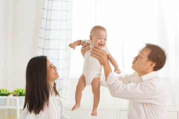 Young happy Asian mom dad and newborn baby infant boy playing at home. © butsaya33