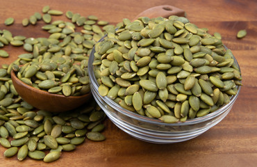 Pumpkin seeds with wooden spoon and glass bowl