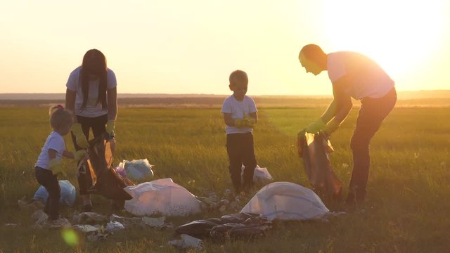 environmental teamwork a ecology teamwork silhouette volunteers awareness pollution household waste sunset time concept. group happy family of people collects garbage pastic and paper waste bottles