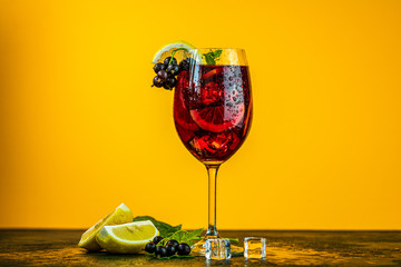 Cold red cocktail with blackcurrant, lemon, mint and ice in tall glass on yellow background. Summer drinks and alcoholic cocktails. Alcoholic cocktail Blackcurrant mojito