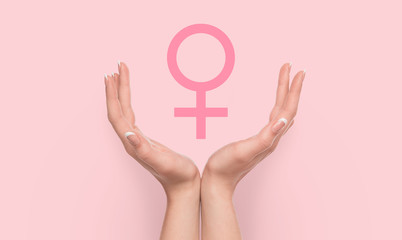 Woman hands holding female gender sign on pink background.