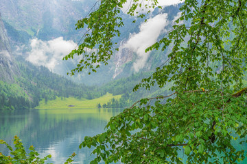 A clear mountain lake with dark clouds and high mountains in the background - 296349032