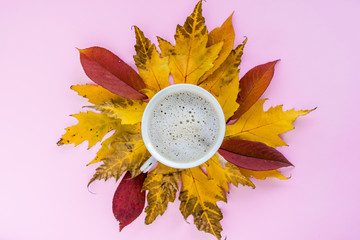 Autumn composition. mug of cappuccino and yellow and red leaves on a pink background. autumn background. flat lay, top view, copy space