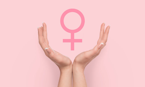Woman hands holding female gender sign on pink background.
