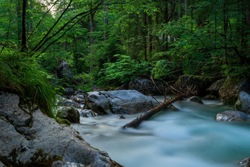 A river in the mountains with stones and green trees as a long exposure - 296349480