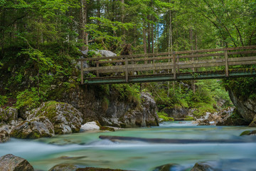 A river in the mountains with stones and green trees as a long exposure