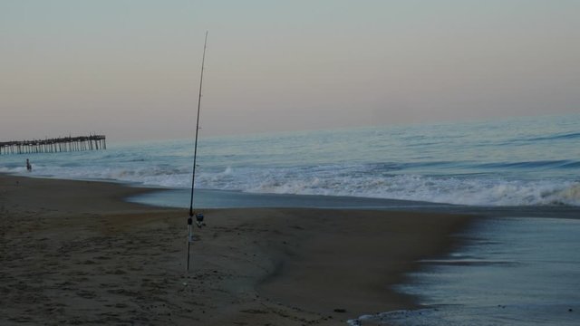ocean waves crashing with fishing pole at sunset
