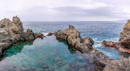 Lonely fisherman over natural pool of Charco de la Laja at the north coast of Tenerife (Canary Islands)