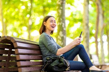  happy older woman sitting in park with mobile phone