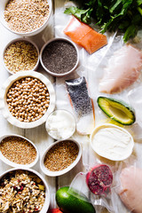 Variety of raw cereals  on  bowls, top view flat lay,lentils, bulgur and quinoa, hemp seed,sunflower seeds ,brown rice, rice, with some healthy food vacccum sealed salmon,avocado,chicken breast,concep