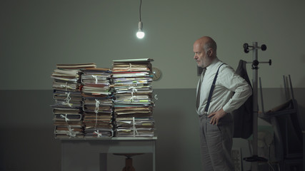 Business executive staring at the stacked paperwork on his desk