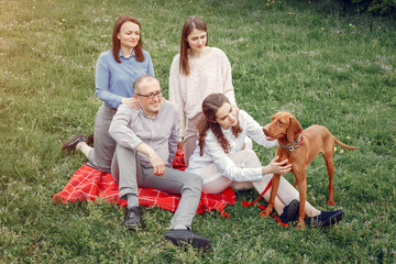 Family in a summer park. People sitting with a dog. Parents with a two daughters