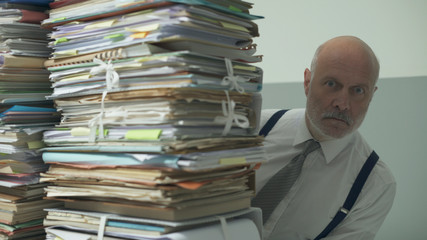 Stressed business executive overloaded with paperwork
