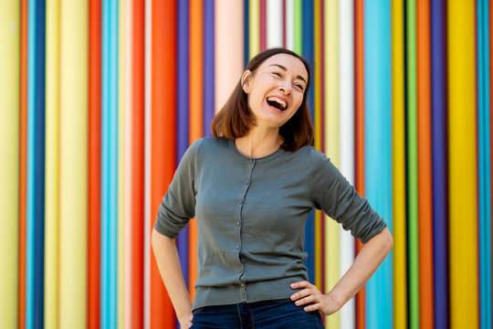 Horizontal Happy Older Woman Laughing With Hands On Hips By Colorful Background