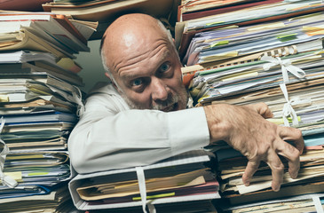 Panicked businessman overloaded with paperwork