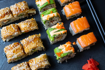Set of fresh sushi rolls with eel, avocado and salmon on black slate board. Overhead flat lay