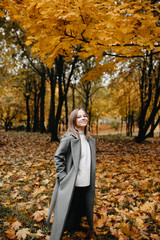 Autumn portrait of a young girl in a park in a gray coat. 