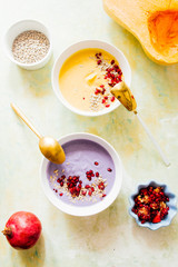 It's soup season, two bowls full of pumpkin and coconut soup one and the other violet potatoes soup, on a green and yellow  background,flat lay composition, healthy warm food for autumnal and winter s