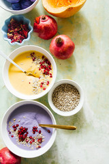 It's soup season, two bowls full of pumpkin and coconut soup one and the other violet potatoes soup, on a green and yellow  background,flat lay composition, healthy warm food for autumnal and winter s