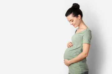 Beautiful young pregnant woman on light background