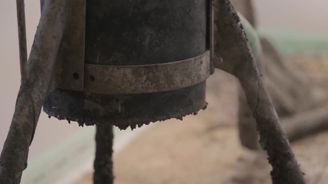 Steel tripod has thin dust evaporating from its bottom. Indoor construction site, heating / boiling in three legged iron device, close up.