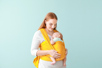 Mother with cute baby on color background