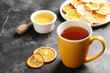 A cup of tea close-up on a dark background with dry citruses and honey. Top view.