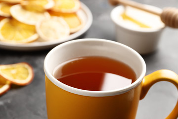 A cup of tea close-up on a dark background with dry citruses and honey. Top view.