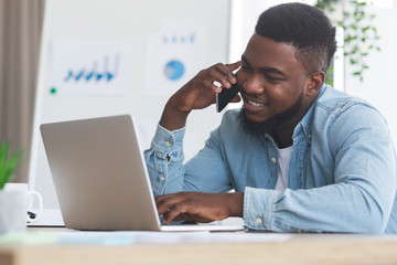 Employee talking on cellphone and working on laptop in office