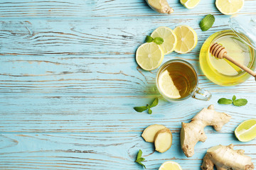 cup of hot tea with ginger, lemon and mint on a white wooden background