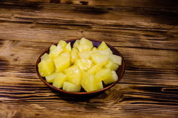 Ceramic plate with chopped canned pineapple on wooden table