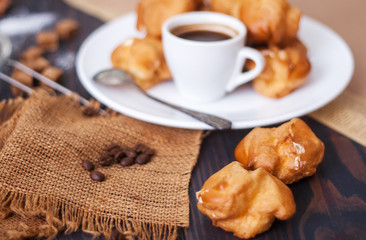 Cup of hot black coffee with home made profiteroles on a rustic table
