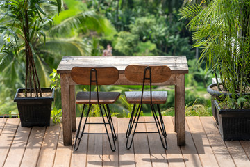 Wooden table and chairs in empty tropical cafe next to rice terraces in island Bali, Indonesia