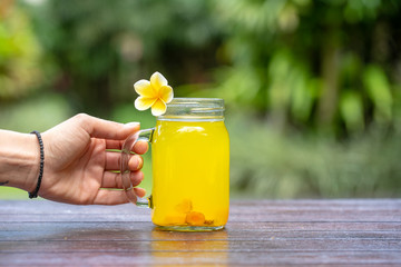 Energy tonic drink with turmeric, ginger, lemon and honey in glass mug, nature background, close up