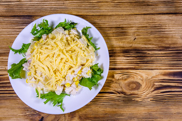 Festive salad with chicken breast, canned pineapple, cheese, sweet corn and mayonnaise on wooden table. Top view