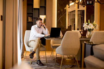 Business man sitting in a luxurious room in front of a laptop