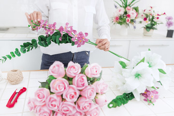 young women business owner florist making or Arranging Artificial flowers vest in her shop, craft and hand made concept