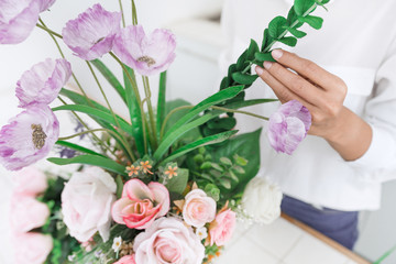 young women business owner florist making or Arranging Artificial flowers vest in her shop, craft and hand made concept