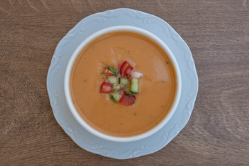 Vegetable cream soup with tomato, potato, squash in a white bowl, closeup