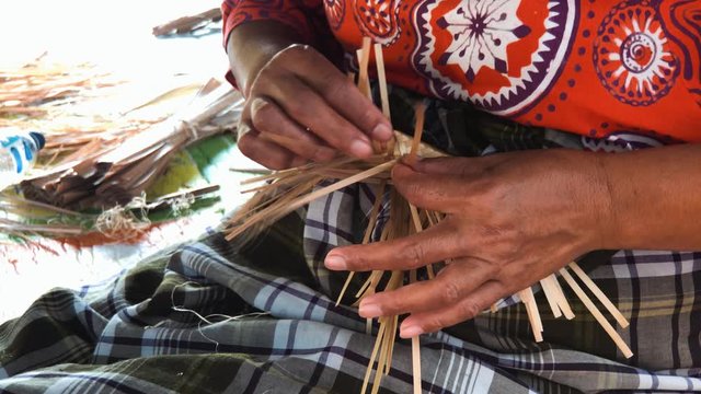 Close up shot of a woman's hand working on a traditional bamboo handwork
