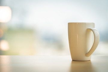 White coffee mug on the table with blurred background.