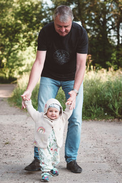Little girl making her first steps with her grandfather