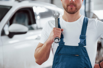 Man with light beard. Employee in the blue colored uniform works in the automobile salon