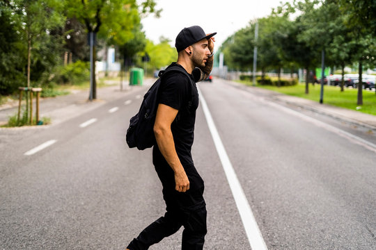 Young man with backpack crossing a street in the city
