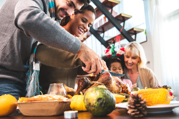 Thanksgiving Celebration Tradition Family Dinner Concept.family having holiday dinner and cutting turkey.Young black adult woman and her daughter happy..