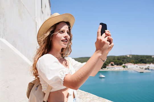 Young woman taking a selfie at the coast, Menorca, Spain