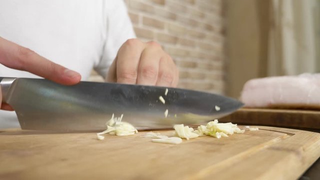 male hands cut garlic on a wooden board. close-up
