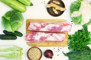 Raw meat, fresh green vegetables, cereals, spices on a white background. Balanced diet concept, flexitarian diet, healthy food. Ingredients for cooking. Top view with copy space for text.