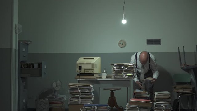 Disorganized businessman searching files in his office