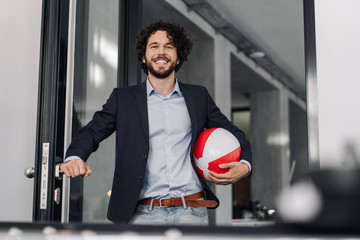 Happy businessman holding beach ball in office